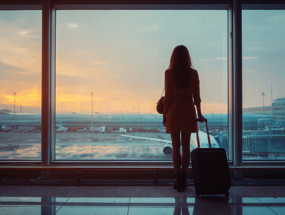 A traveller looking across an airport runway at sunrise